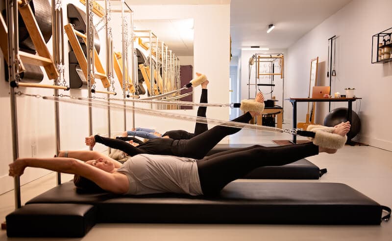 Three clients on mats under the wall-mounted Towers in warm lamp light