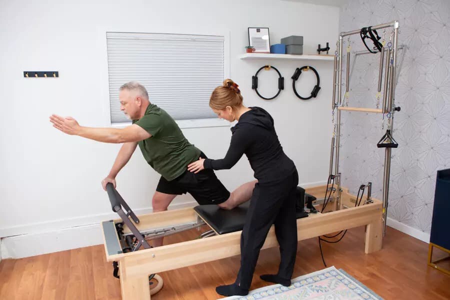 A therapist cueing a client kneeling on the Reformer in the Wellness Suite at Contrology Studio