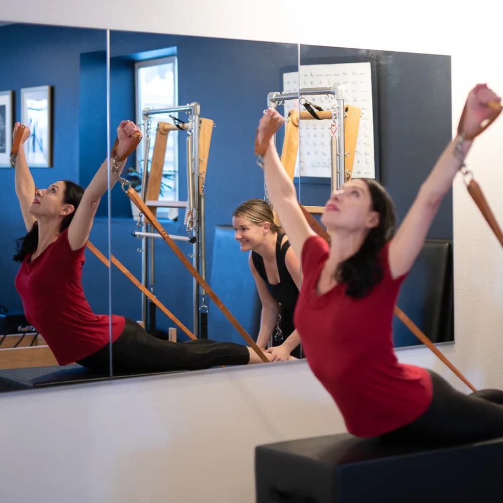 A client working arm springs seated on a box, reflected in the studio mirrors